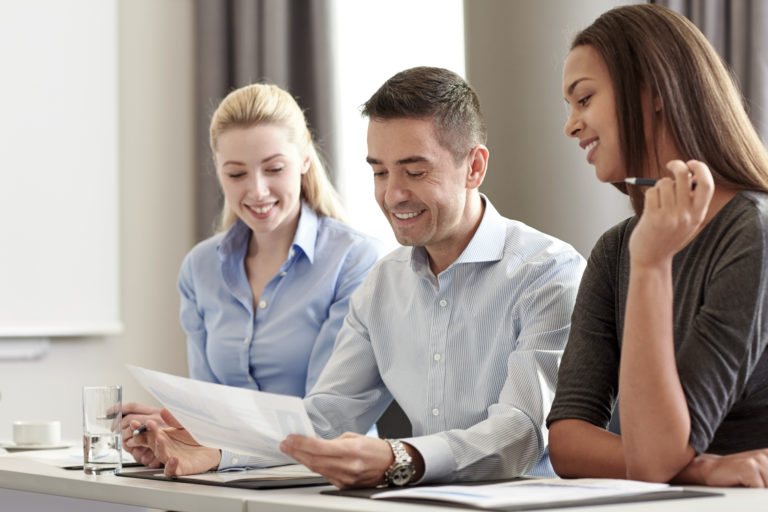 People discussing the contents of a sheet of paper in a meeting.