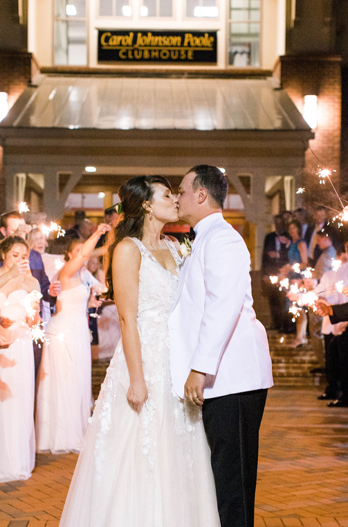 A bride and groom kiss outside the Carol Johnson Poole Clubhouse.